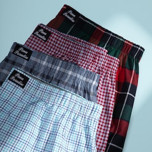 May include: Four pairs of plaid boxer shorts in various colors, including red, blue, and green. Each pair has the text "Pima Paradise" on the waistband. The shorts are made of a soft, comfortable material.