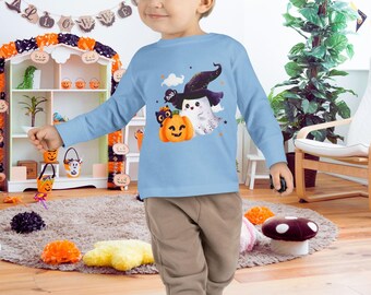Puede incluir: Una camiseta de manga larga azul claro con un diseño de Halloween. El diseño incluye una calabaza sonriente, un fantasma con un sombrero de bruja y un gato negro. La camiseta está hecha de un material suave y es adecuada para niños.