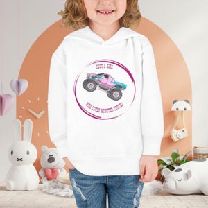 May include: White hooded sweatshirt with a pink and blue monster truck graphic and the text "Just a girl who loves monster trucks".