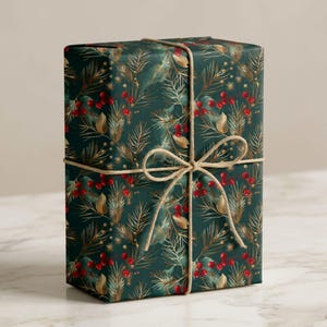 May include: A rectangular gift box wrapped in dark green paper featuring a repeating pattern of gold pine needles and bright red berries. The package is tied with a thin, natural-coloured jute twine string that is knotted into a bow at the centre.
