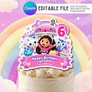 Puede incluir: Un adorno para pastel con una niña de dibujos animados de cabello castaño y orejas de gato, rodeada de gatos coloridos, una casa rosa y el número 6. Una cinta rosa en la parte inferior muestra el texto Happy Birthday Gabriela en blanco.