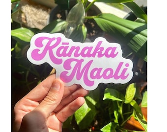 May include: Pink and white sticker with the text "Kānaka Maoli" in a retro font.