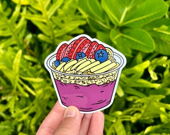 May include: A sticker of a purple acai bowl with sliced strawberries, blueberries, and granola. The bowl is in a white to-go container.