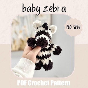 Może przedstawiać: Ręcznie robiona szydełkowa zabawka w kształcie zebry w kolorze czarno-białym. Obraz zawiera tekst "baby zebra" i "NO SEW". Na dole obrazu widnieje napis "PDF Crochet Pattern". Zebra ma czarną grzywę, uszy i kończyny.