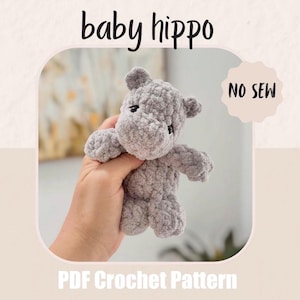 Op de afbeelding: Een grijs gehaakt baby nijlpaard knuffel. De knuffel heeft kleine oren, een afgerond lichaam en korte ledematen. De tekst "baby hippo" staat bovenaan de afbeelding en "NO SEW" staat in een cirkelvorm. "PDF Crochet Pattern" staat onderaan.