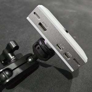 May include: A white camera with a black tripod mount. The camera has HDMI, USB, and PWR ports.