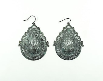 May include: A pair of silver filigree earrings with a teardrop shape. The earrings have a delicate, intricate design and a slightly oxidised finish.