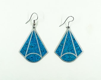 May include: A pair of silver earrings with a geometric design. The earrings are decorated with turquoise blue stones.