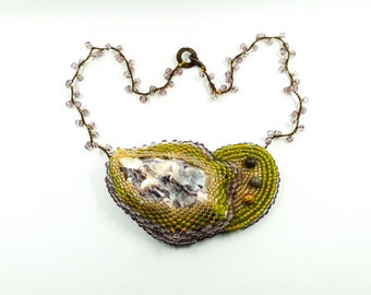 May include: A beaded necklace with a large, irregularly shaped pendant featuring a natural stone and green and purple beads.