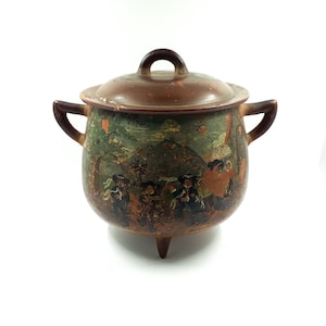 Peut inclure: Un pot en céramique brun avec un couvercle et trois pieds. Le pot est décoré d'une scène peinte de personnes dans un paysage.