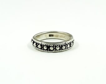 May include: A silver ring with a beaded pattern. The ring has a series of small, raised beads around the band, with a rope-like texture between them. The ring is on a white background.