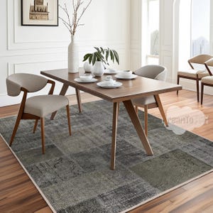 Puede incluir: Una alfombra de patchwork gris y negro con una mesa de comedor de madera y sillas. La mesa tiene una tapa de madera y una alfombra de patchwork gris y negro debajo.