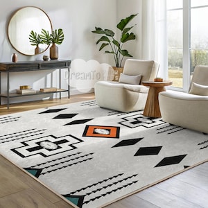 May include: A white and black geometric patterned rug with orange and teal accents. The rug is laid out on a wooden floor in a living room setting with two white armchairs and a wooden side table.