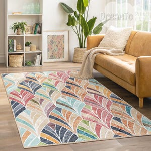 May include: A colorful area rug with a geometric pattern of overlapping, multi-colored leaves. The rug has a cream background with shades of blue, green, pink, orange, and yellow.