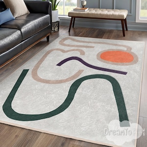May include: A rectangular area rug with an abstract design. The rug features a light gray background with curved lines in dark green, tan, purple, and orange. The rug is placed on a hardwood floor.