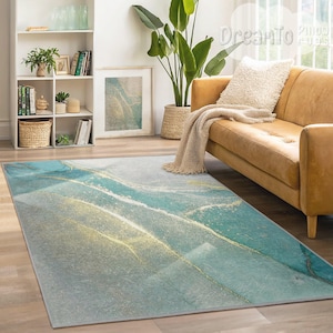 May include: Abstract area rug with a blue, green, and gold marble design. The rug is laid out on a wooden floor in a living room setting with a couch and a potted plant.