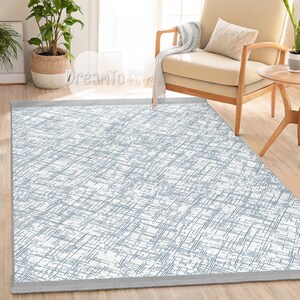 May include: A white and blue patterned area rug with a gray border. The rug has a subtle, distressed look and is perfect for adding a touch of modern style to any room.