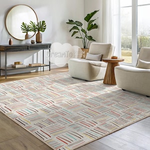 Pode incluir: Um tapete branco com um padrão geométrico de linhas coloridas. O tapete está em uma sala de estar com duas poltronas brancas e uma mesa de apoio de madeira.