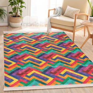 Op de afbeelding: Een rechthoekig vloerkleed met een levendig geometrisch patroon. Het ontwerp heeft een herhalend zigzagpatroon in een spectrum van kleuren, waaronder rood, geel, blauw, groen en paars. Het vloerkleed heeft een witte rand en de tekst "DreamTo Pugs" is zichtbaar.