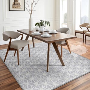 Puede incluir: Una alfombra geométrica gris y blanca con una mesa de comedor de madera y sillas en un comedor moderno.