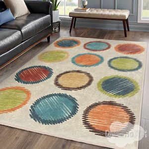 May include: A rectangular area rug with a cream background and large, colorful, scribbled circles in shades of blue, orange, green, and brown. The rug is placed on a hardwood floor, and the design adds a playful touch to the room.