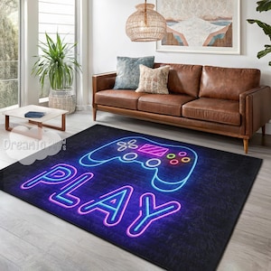 May include: A rectangular black rug with a neon-style design. The rug features a glowing blue and pink controller graphic above the word "PLAY" in a similar neon style. The rug is placed on a wooden floor in a living room setting.