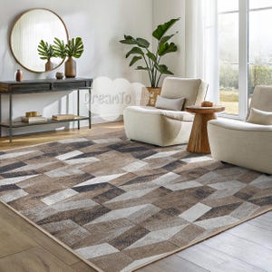 May include: A geometric patterned area rug in shades of brown, gray, and white. The rug is laid out on a hardwood floor in a living room setting with two white armchairs and a wooden side table.