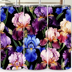Peut inclure: Trois gobelets en acier inoxydable avec un motif floral vibrant. Le motif présente des fleurs d'iris colorées dans des tons de violet, de bleu, de rose et de jaune sur un fond noir. Chaque gobelet a un couvercle argenté et une paille.