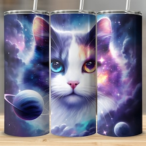 May include: A stainless steel tumbler with a colorful design featuring a cat's face with blue and yellow eyes, surrounded by a galaxy-like background with stars and planets.