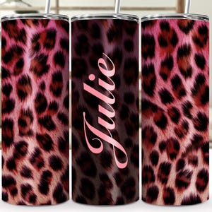 May include: A set of three stainless steel tumblers with a pink and brown leopard print design. The center tumbler has the name "Julie" in a pink script font. Each tumbler has a silver lid and a straw.