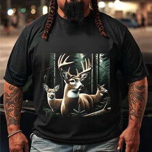 Puede incluir: Una camiseta negra de manga corta con un estampado gr&aacute;fico de tres ciervos en un bosque oscuro. El ciervo central tiene astas grandes, mientras que los dos ciervos a los lados son m&aacute;s peque&ntilde;os. La escena del bosque incluye &aacute;rboles altos.