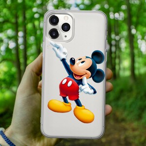 May include: A clear phone case with a white background and a cartoon image of Mickey Mouse in red shorts and yellow shoes. Mickey Mouse is waving with his right hand and giving a thumbs up with his left hand.