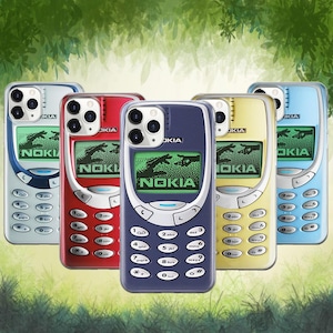 May include: Five smartphone cases featuring a retro Nokia 3310 design in silver, red, dark blue, yellow, and light blue. Each case displays a pixelated screen graphic showing two hands reaching toward each other with the Nokia logo below.