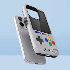 Może przedstawiać: Białe etui na telefon zaprojektowane tak, aby przypominało Game Boy Color. Etui posiada czarny ekran, krzyżak i kolorowe przyciski. Na etui wydrukowano napis "GAME BOY COLOR".