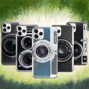 May include: A collection of phone cases designed to resemble vintage cameras. The cases feature detailed camera lens designs, with brands like Canon, Zeiss Ikon, and Minolta. The cases are in various colors, including black and blue, with realistic dials and text.