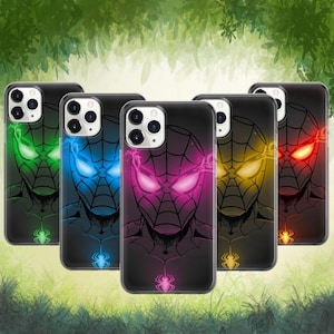 Puede incluir: Una colección de cinco fundas negras para teléfono con un diseño de Spider-Man con ojos brillantes en verde, azul, rosa, amarillo y rojo. Cada funda tiene un emblema de araña en la parte inferior. Las fundas se muestran sobre un fondo verde borroso.