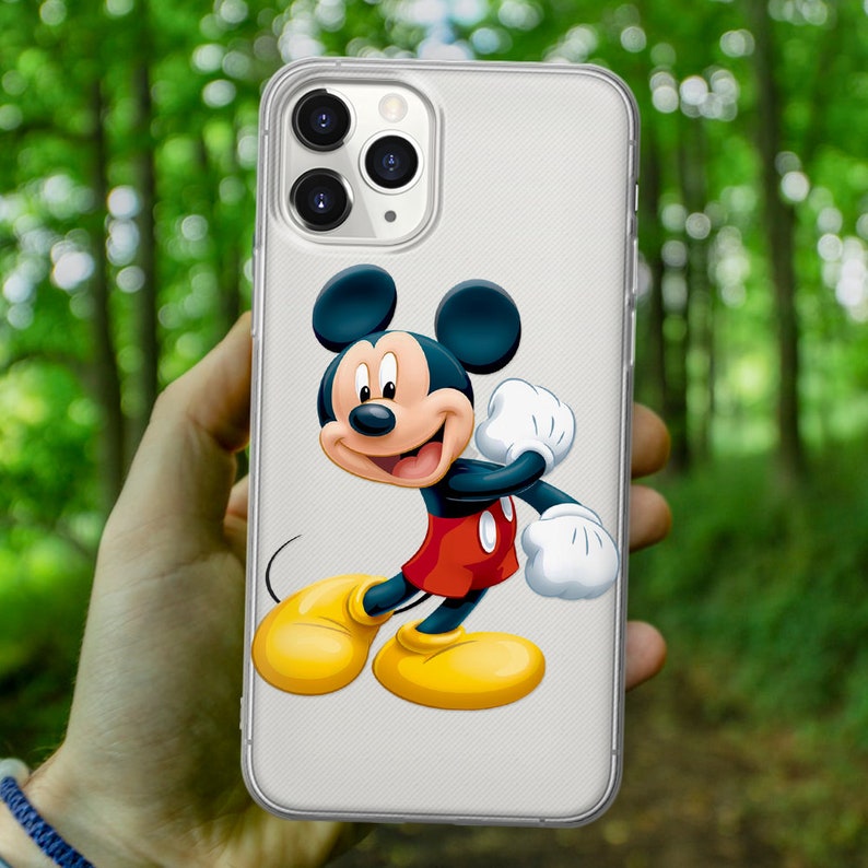 May include: A clear phone case with a white background and a cartoon image of Mickey Mouse in a red and yellow outfit. Mickey Mouse is waving with his right hand and has a big smile on his face.