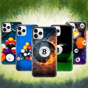 May include: A collection of phone cases featuring billiard ball designs. The cases display various pool ball graphics, including the number 8 ball with flames, and other balls on a blue and green background. The cases are shown in a row.