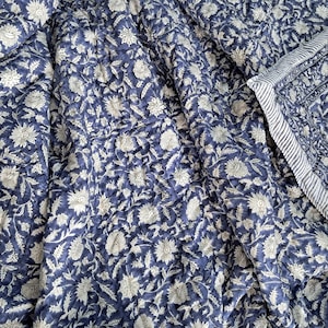 Peut inclure: Une courtepointe à motifs floraux bleus et blancs avec une bordure rayée blanche et bleue. La courtepointe est en coton et est parfaite pour ajouter une touche d'élégance à n'importe quelle chambre.