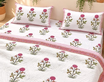 May include: A white bedspread and two matching pillowcases featuring a repeating floral pattern of pink circular blossoms with green stems and leaves. The bedding set includes a quilted texture and a pink patterned border along the edges.