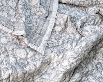 May include: A grey and white patterned quilt with a white border. The quilt is made of a soft, lightweight fabric and is perfect for keeping warm on chilly nights.