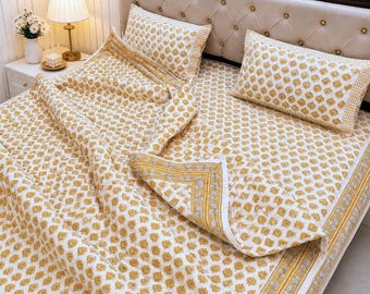 May include: A bedding set featuring a white base with a repeating mustard yellow floral block print pattern. The set includes a quilted coverlet and two matching rectangular pillow shams, all finished with a coordinating yellow and white border.