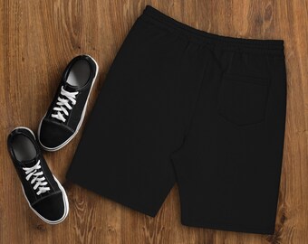 May include: Black sweat shorts with a drawstring waist and a back pocket. The shorts are laid flat on a wooden surface.