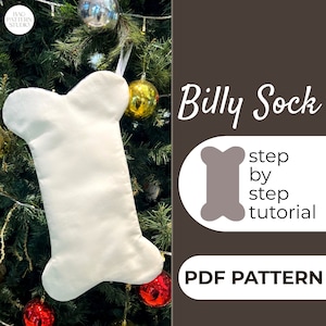 Op de afbeelding: Een witte, botvormige kerstsok hangt aan een groene kerstboom met rode en gouden kerstballen. De tekst "Billy Sock" is geschreven in zwarte cursieve letters. De tekst "step by step tutorial" is geschreven in zwarte letters. De tekst "PDF PATTERN" is geschreven in zwarte letters.