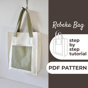 May include: A white tote bag with a green and white striped pocket and straps. The bag is hanging on a silver hook against a white wall. Text on the right side reads "Rebeka Bag", "step by step tutorial", and "PDF PATTERN".