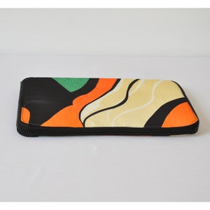 May include: A black zippered pouch with a colorful abstract design featuring orange, green, and cream waves.