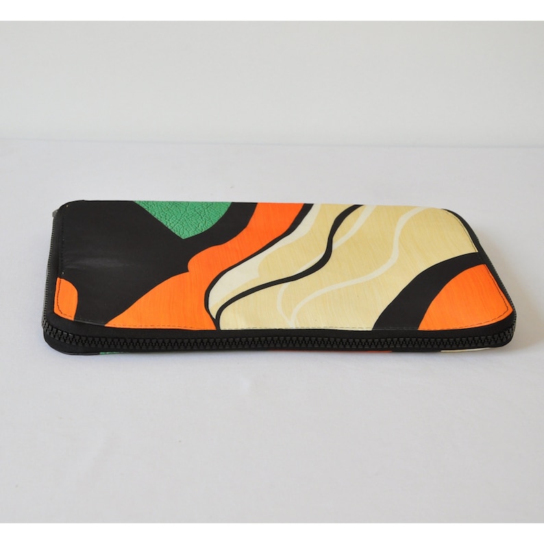 May include: A black zippered pouch with a colorful abstract design featuring orange, green, and cream waves.