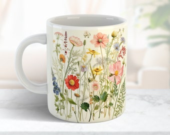 May include: White ceramic mug with a floral design featuring a variety of pink, red, yellow, and blue flowers on a cream background.