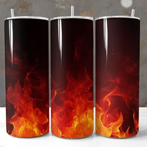 May include: Three stainless steel tumblers with a fiery orange and red flame design. The tumblers are on a white surface.