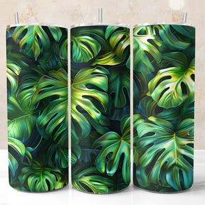 Könnte beinhalten: Drei Edelstahlbecher mit tropischem Blattdesign. Die Becher sind grün und schwarz mit glänzender Oberfläche.